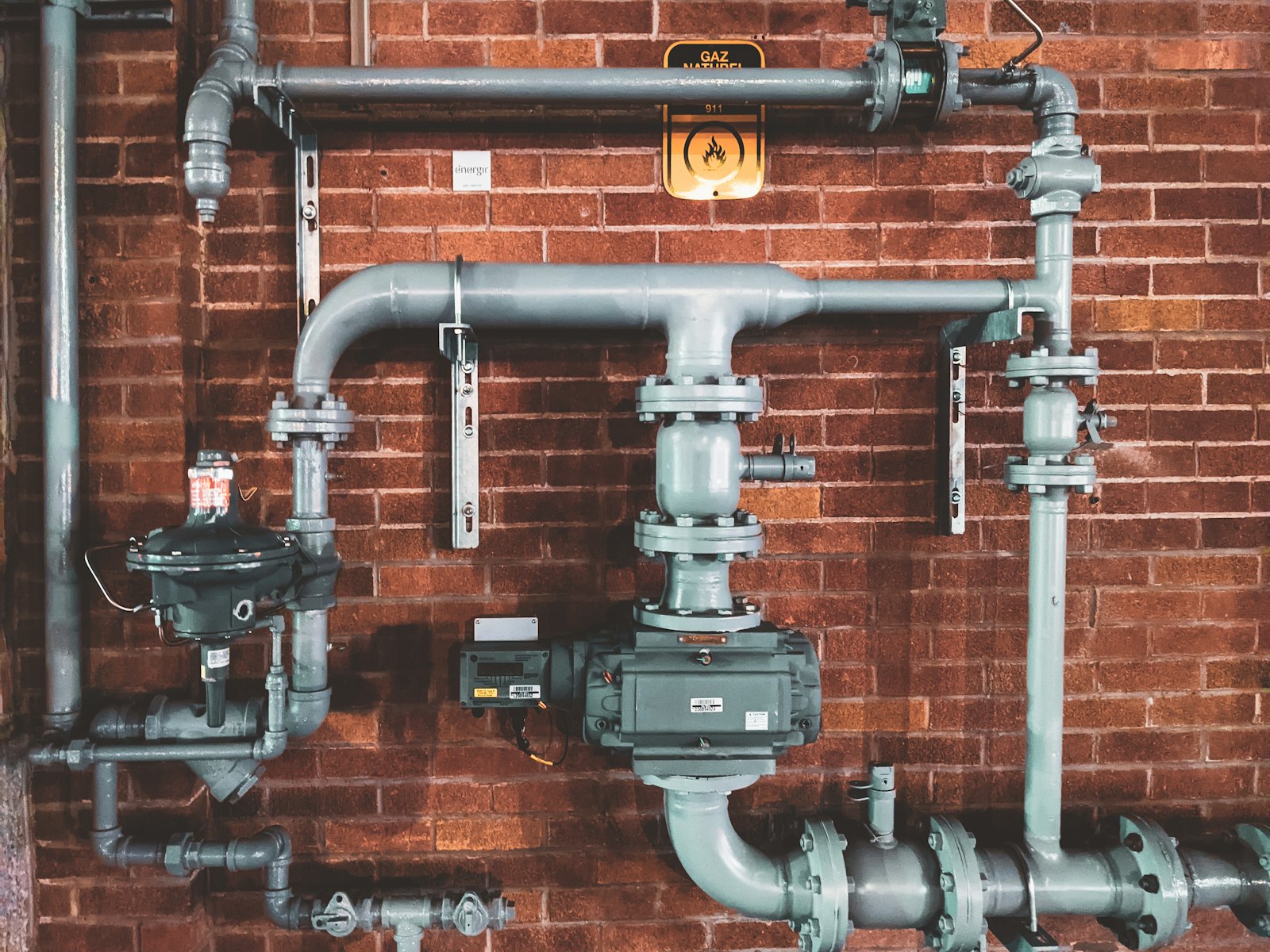 Exposed pipes and valves on a brick wall