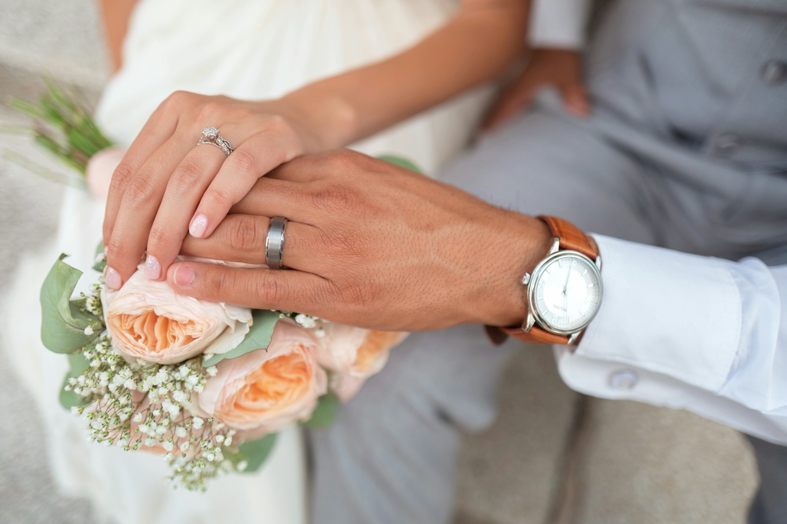 Hands with wedding rings and bouquet